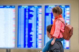 menina com seu pai informações de voo de fundo no aeroporto foto