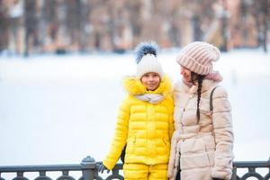 menina adorável com sua mãe patinando na pista de gelo foto