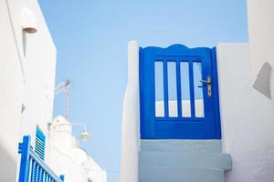 casas tradicionais com porta azul e escadas brancas nas ruas estreitas de mykonos, grécia. foto