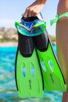 óculos de mergulho, snorkel e barbatanas de mergulho nas mãos da mulher foto