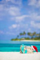 acessórios de praia com chapéu de Papai Noel na praia tropical branca foto