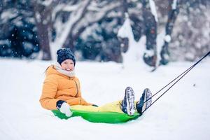 adorável menina feliz trenó em dia de inverno nevado. foto