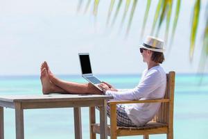 jovem trabalhando no laptop durante as férias de verão foto