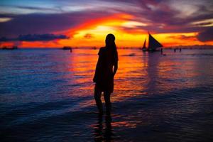 jovem mulher bonita na praia tropical ao pôr do sol foto