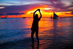 jovem mulher bonita na praia tropical ao pôr do sol foto