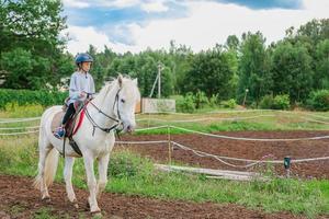 menina montando um cavalo branco na natureza foto