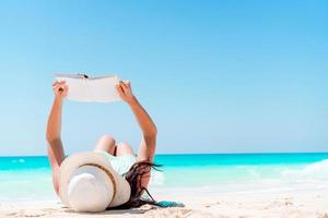 jovem lendo livro durante a praia branca tropical foto