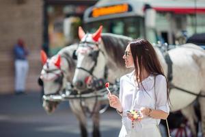 garota turista curtindo um passeio por viena e olhando para os belos cavalos na carruagem foto