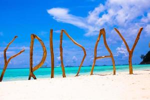 praia de areia branca perfeita e mar turquesa na ilha tropical com letras de madeira feitas sexta-feira palavra foto