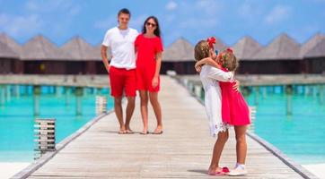 jovem família de quatro pessoas se diverte no cais de madeira durante as férias de verão foto