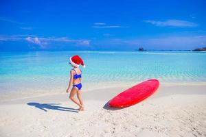 menina de chapéu de Papai Noel na praia durante as férias foto