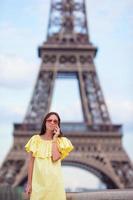 jovem mulher falando por telefone fundo torre eiffel em paris foto