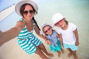 mãe e filhas tomando selfie na praia tropical foto