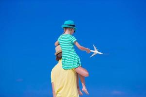 jovem e menina com miniatura de avião na praia foto