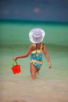 menina brincando na praia e tomando água em um balde foto