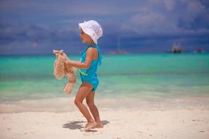 menina adorável com seu brinquedo favorito em férias de praia tropical foto