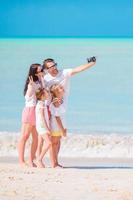 família tirando uma foto de selfie na praia. férias em família na praia