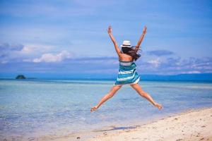 jovem pulando e levantando os braços na praia foto