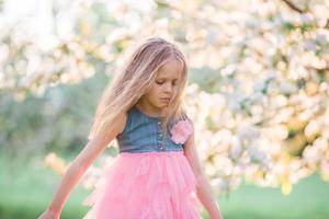 adorável menina aproveitando o dia de primavera no jardim de florescência de maçã foto