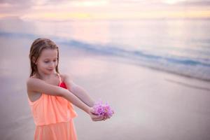 linda garotinha de vestido na praia se divertindo. garota engraçada aproveite as férias de verão. foto