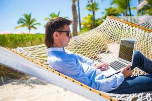 jovem trabalhando com laptop na rede durante as férias na praia foto