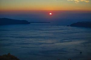 famoso pôr do sol acima da vista da caldeira sobre o mar na ilha de santorini foto