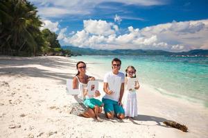 jovem família feliz de quatro pessoas em férias tropicais com a palavra amor foto