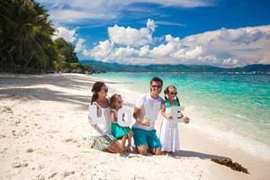 família de quatro pessoas em férias na praia foto