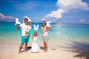 jovem família feliz de quatro pessoas em férias tropicais com a palavra amor foto