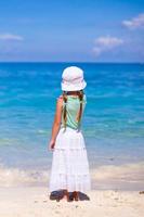 vista traseira da adorável garotinha em uma praia exótica foto