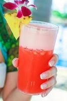 coquetel vermelho tropical na mão de uma jovem em um resort exótico foto