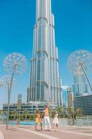 família feliz andando em dubai com o arranha-céu burj khalifa ao fundo. foto