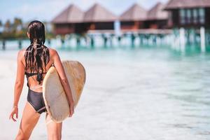 linda surfista pronta para surfar no mar azul-turquesa, na prancha de stand up paddle em férias exóticas foto