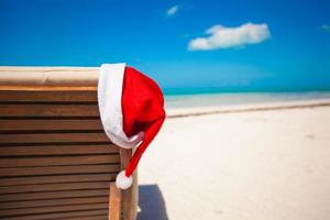 chapéu de papai noel na cadeira longue na praia tropical do caribe foto