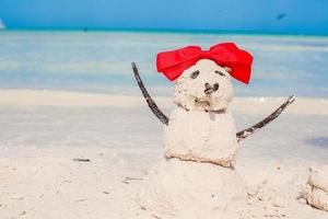 pequeno boneco de neve de areia com arco na praia branca do caribe foto