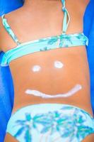 sorriso de close-up pintado por protetor solar nas costas da criança foto