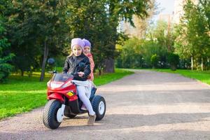 adoráveis meninas andando de moto no parque verde foto