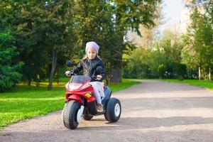 adorável menina se divertindo em sua bicicleta de brinquedo foto