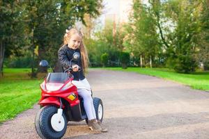 menina adorável se divertindo em sua bicicleta no parque verde foto