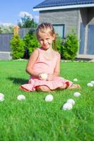 menina adorável brincando com ovos de páscoa brancos no quintal foto