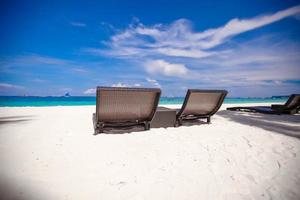 cadeiras de madeira de praia para férias e relaxar na praia tropical de areia branca foto