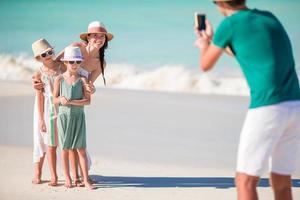 família de quatro pessoas tirando uma foto de selfie em suas férias na praia.