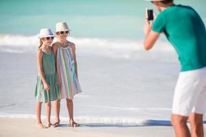 homem tirando uma foto de seus filhos na praia