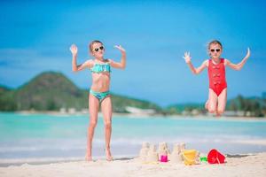 duas crianças fazendo castelo de areia e se divertindo na praia tropical foto