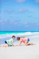 crianças felizes se divertindo muito na praia tropical brincando juntos. adoráveis meninas dançando na ilha caribenha foto