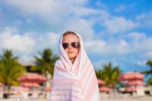 adorável menina coberta com toalha na praia tropical foto