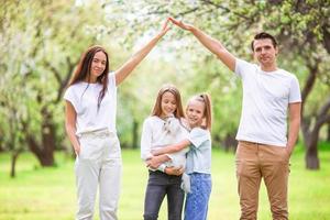 família adorável no jardim cerejeira florescendo em lindo dia de primavera foto