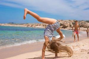 menina adorável fazendo roda na praia de areia branca tropical foto