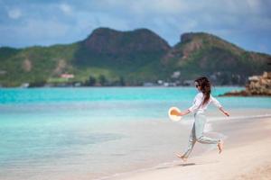 jovem mulher bonita se divertindo na praia tropical. garota feliz correndo na praia tropical de areia branca foto