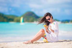 jovem mulher com telefone na praia tropical. linda garota na praia com celular na ilha caribenha foto